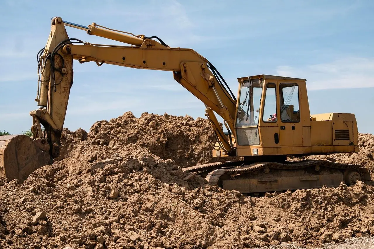 Yellow excavator digging into a pile of dirt