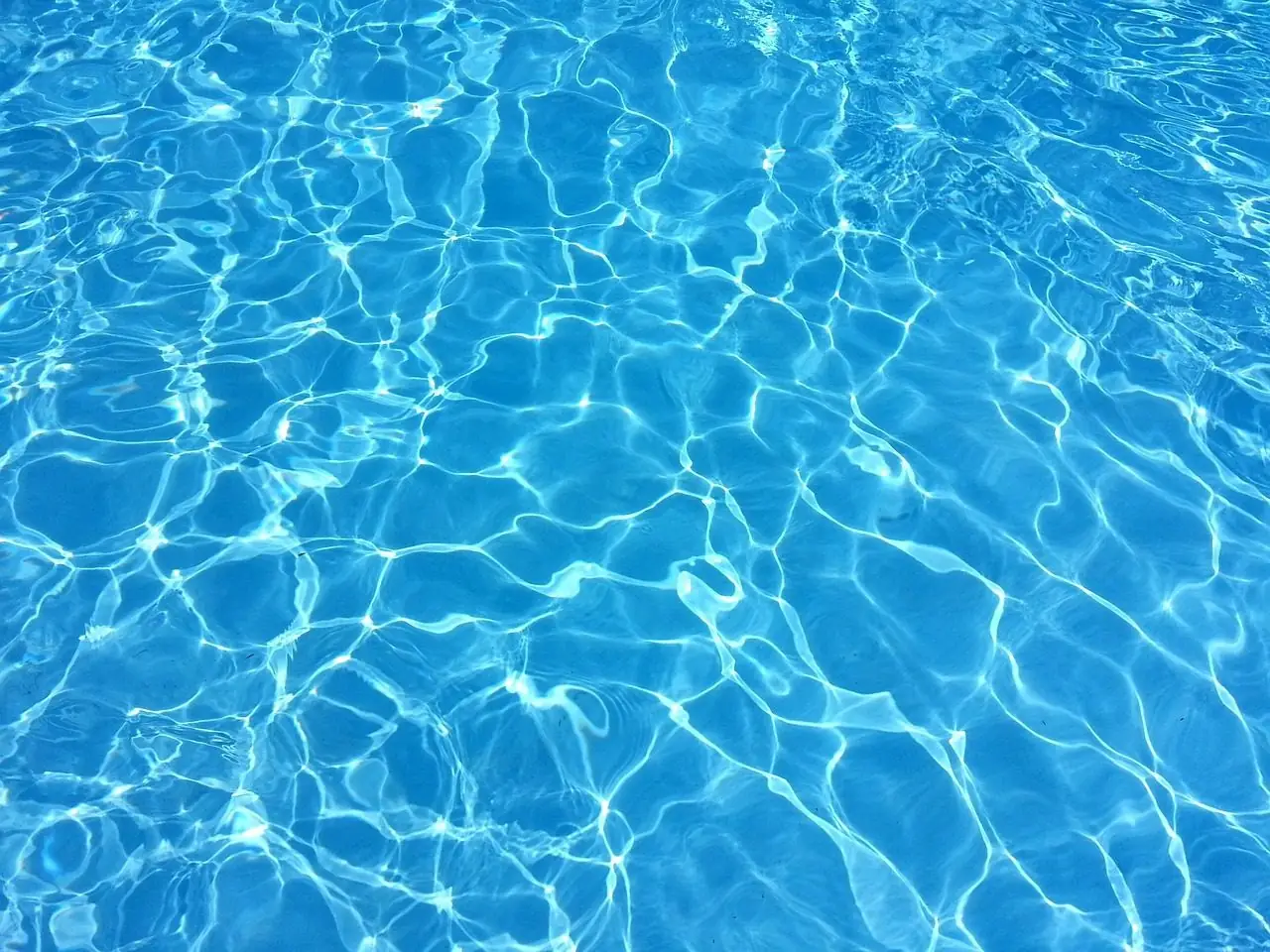 Clear blue pool water with light patterns on the bottom